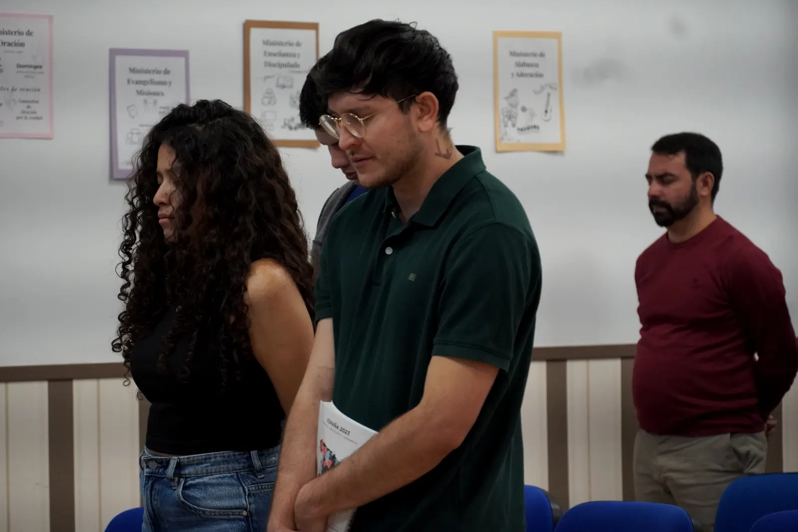 Varios hermanos oran de pie con la cabeza inclinada